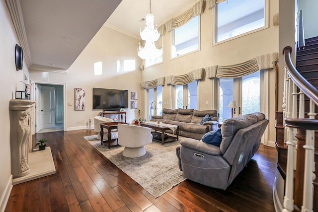 living room with ornamental molding, dark wood-type flooring, an inviting chandelier, and a healthy amount of sunlight