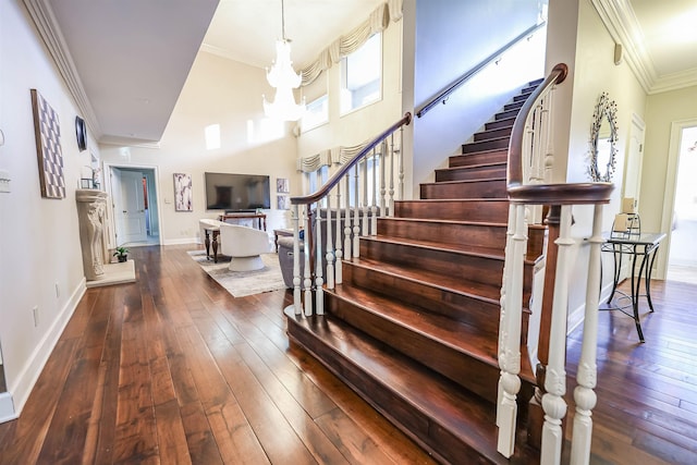 stairway featuring crown molding, a towering ceiling, and wood-type flooring