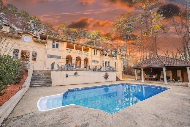 pool at dusk featuring a gazebo and a patio