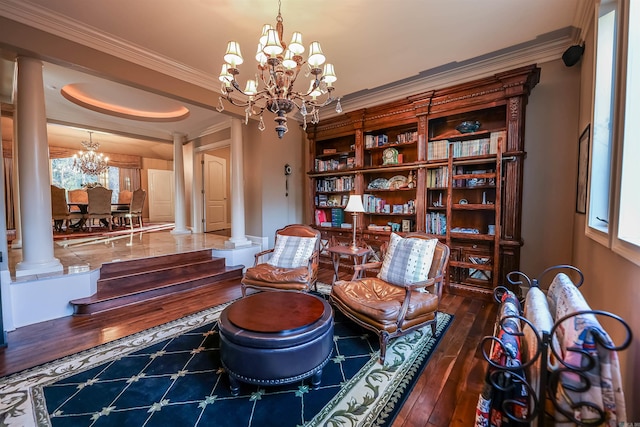 sitting room with dark hardwood / wood-style flooring, crown molding, a chandelier, and ornate columns