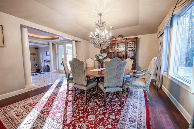 dining area with a raised ceiling, decorative columns, and dark hardwood / wood-style flooring