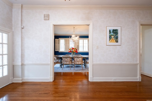 interior space featuring wood-type flooring, ornamental molding, and a chandelier