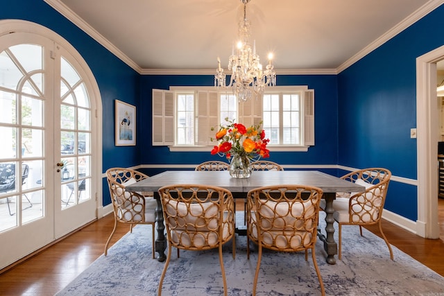 dining area featuring crown molding, hardwood / wood-style floors, an inviting chandelier, and french doors