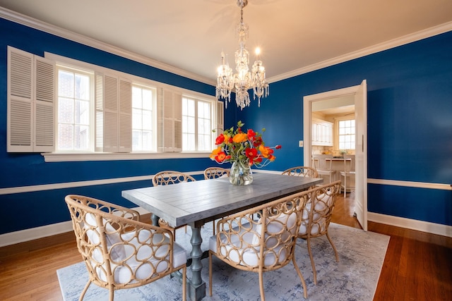 dining area featuring an inviting chandelier, hardwood / wood-style floors, plenty of natural light, and ornamental molding