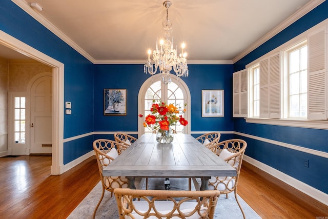 dining space featuring hardwood / wood-style flooring, crown molding, and a notable chandelier