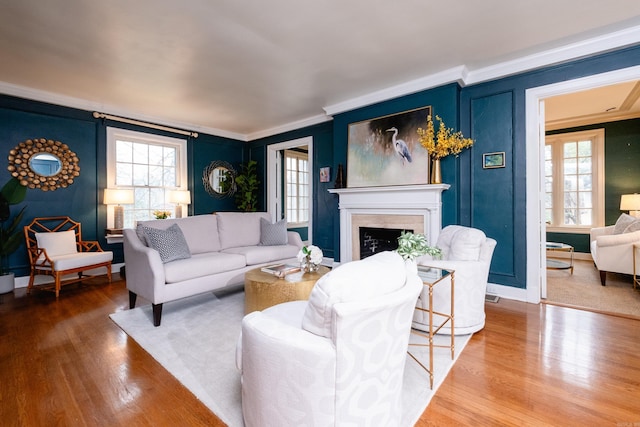 living room featuring wood-type flooring, ornamental molding, and a wealth of natural light