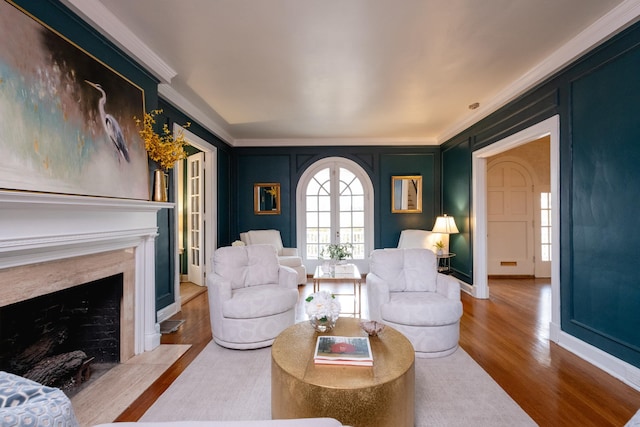 living room with hardwood / wood-style floors, a premium fireplace, ornamental molding, and french doors