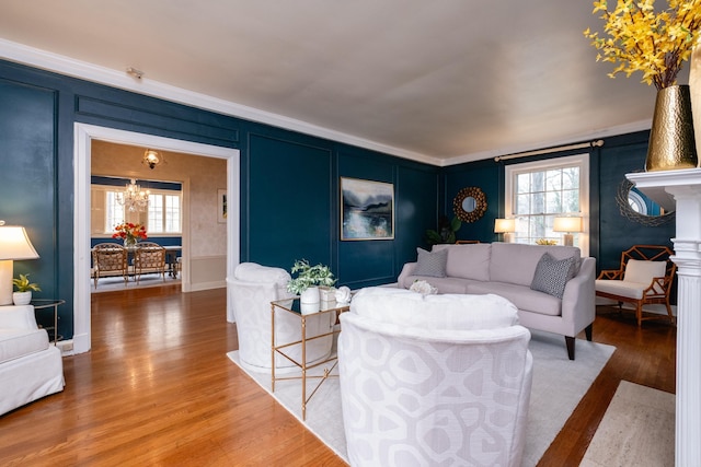 living room with wood-type flooring, crown molding, and an inviting chandelier