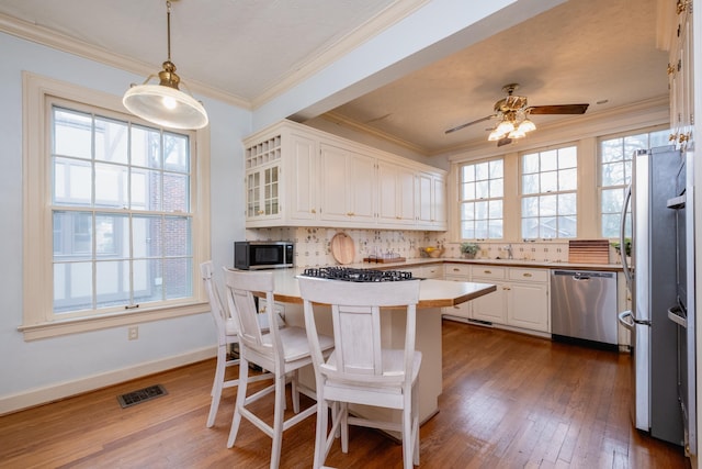 kitchen featuring a breakfast bar, white cabinetry, hanging light fixtures, appliances with stainless steel finishes, and kitchen peninsula