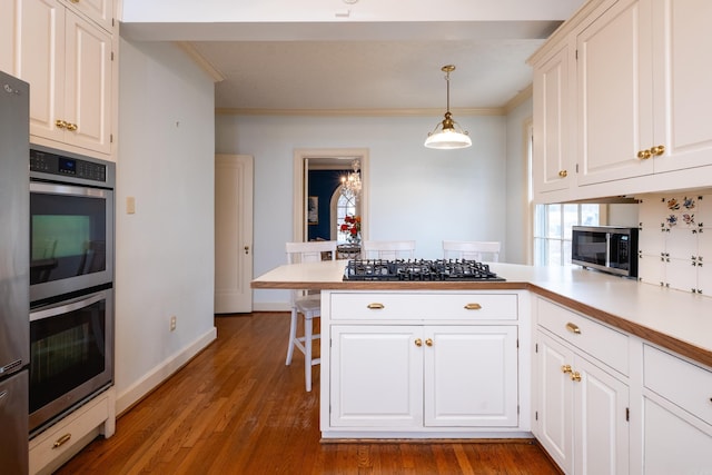 kitchen featuring decorative light fixtures, kitchen peninsula, white cabinets, and appliances with stainless steel finishes