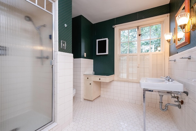 bathroom with a shower with shower door, tile patterned flooring, and tile walls