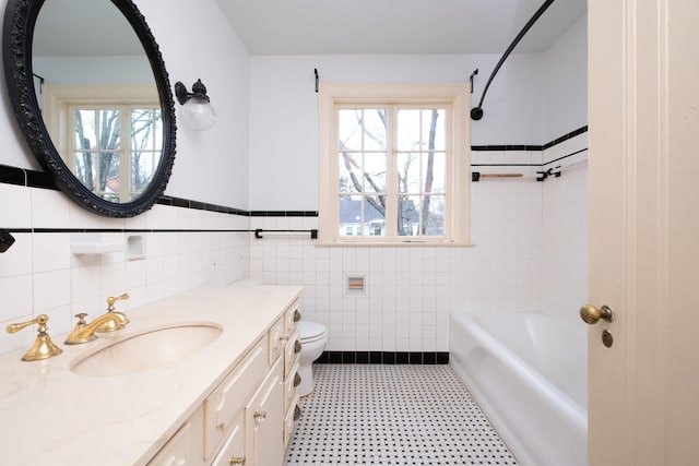 bathroom featuring a healthy amount of sunlight, toilet, tile walls, and vanity