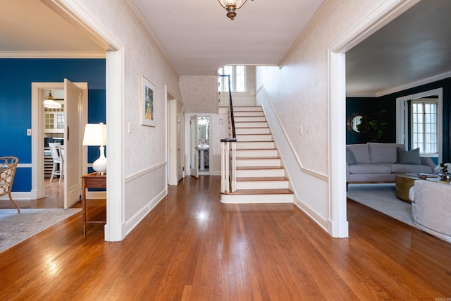 staircase featuring crown molding, a healthy amount of sunlight, and hardwood / wood-style floors