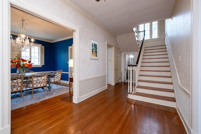 foyer with hardwood / wood-style flooring, crown molding, a healthy amount of sunlight, and a notable chandelier