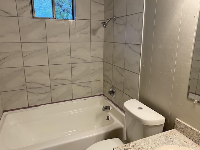 full bathroom featuring tiled shower / bath, vanity, and toilet