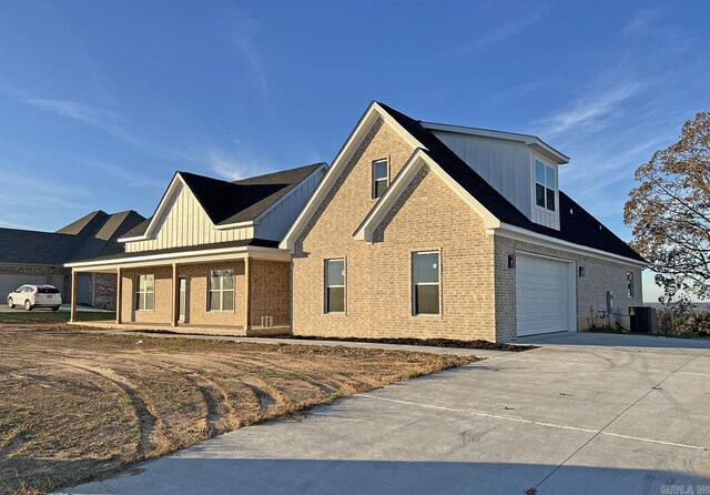 view of front of house featuring central AC unit, a garage, and a porch