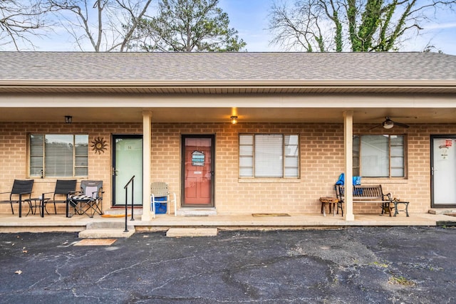 view of front of property with a porch, brick siding, a shingled roof, and a ceiling fan