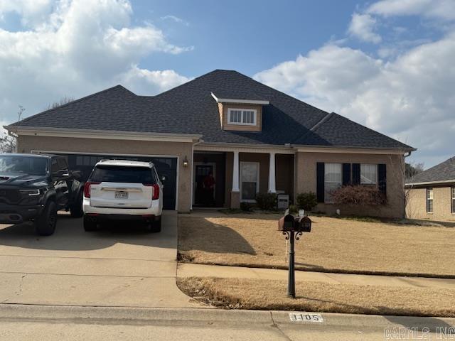 view of front of property featuring concrete driveway, roof with shingles, and an attached garage