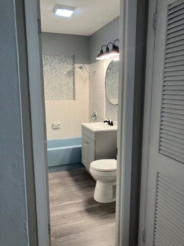 full bathroom with vanity, toilet, tiled shower / bath combo, and hardwood / wood-style floors