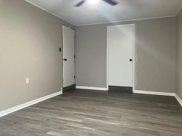 empty room with ornamental molding, dark wood-type flooring, and ceiling fan