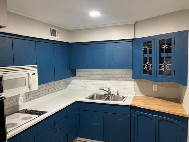 kitchen with tasteful backsplash, sink, white appliances, and blue cabinetry