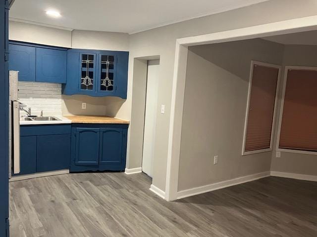 kitchen featuring decorative backsplash, blue cabinets, sink, and hardwood / wood-style floors