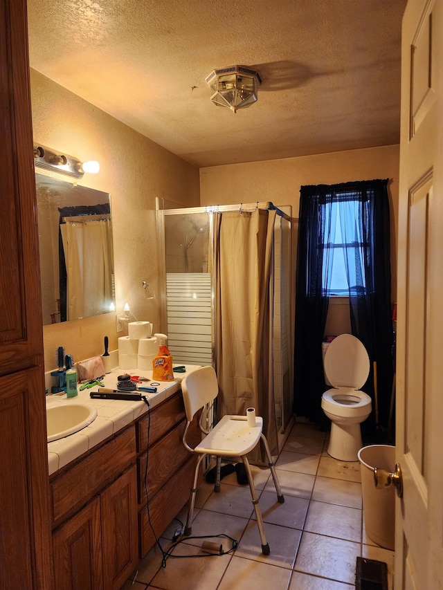 bathroom with vanity, a shower, a textured ceiling, tile patterned floors, and toilet