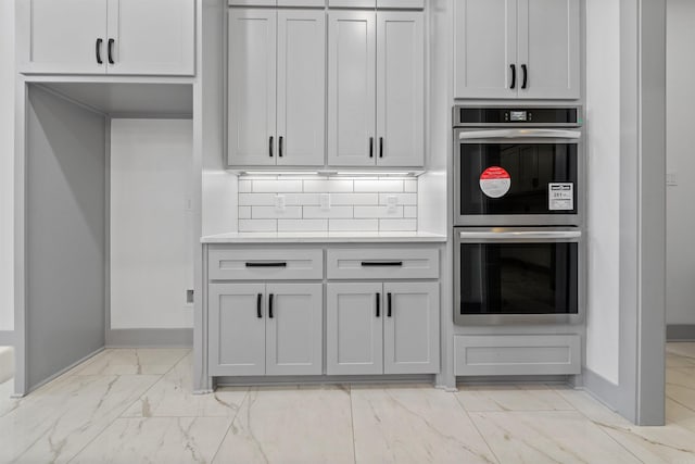 kitchen with tasteful backsplash, gray cabinetry, and stainless steel double oven