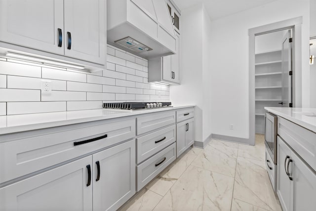 kitchen with white cabinetry, premium range hood, gas cooktop, and decorative backsplash