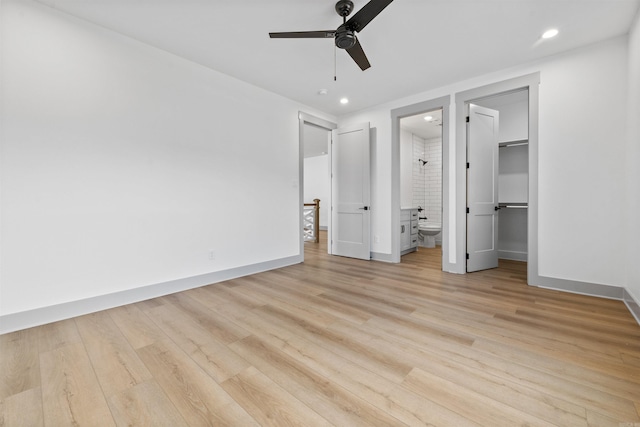 unfurnished bedroom featuring ensuite bathroom, a walk in closet, ceiling fan, and light hardwood / wood-style floors