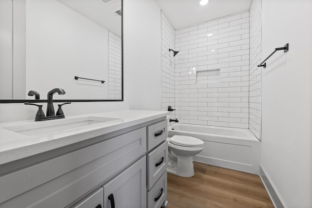 full bathroom featuring hardwood / wood-style flooring, tiled shower / bath, vanity, and toilet