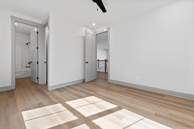 unfurnished bedroom with ceiling fan, ensuite bath, and light wood-type flooring