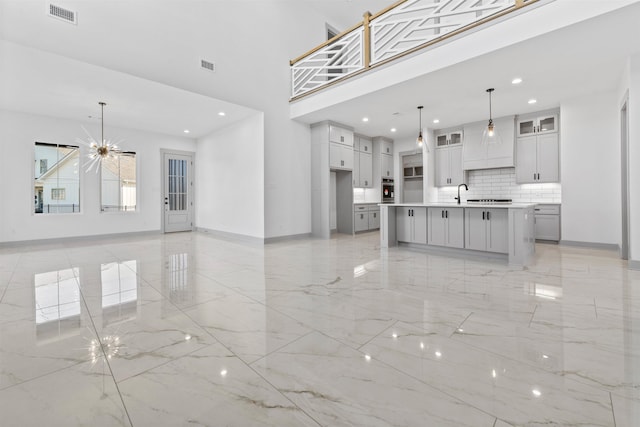 unfurnished living room with a towering ceiling, sink, and a notable chandelier