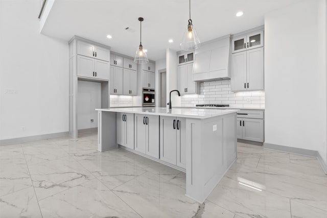 kitchen with premium range hood, sink, decorative light fixtures, a center island with sink, and oven