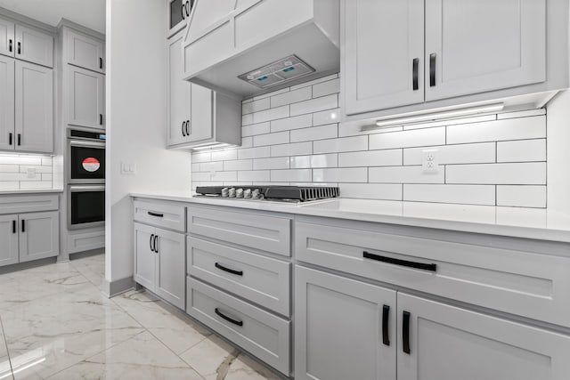 kitchen with gray cabinetry, backsplash, custom range hood, and appliances with stainless steel finishes