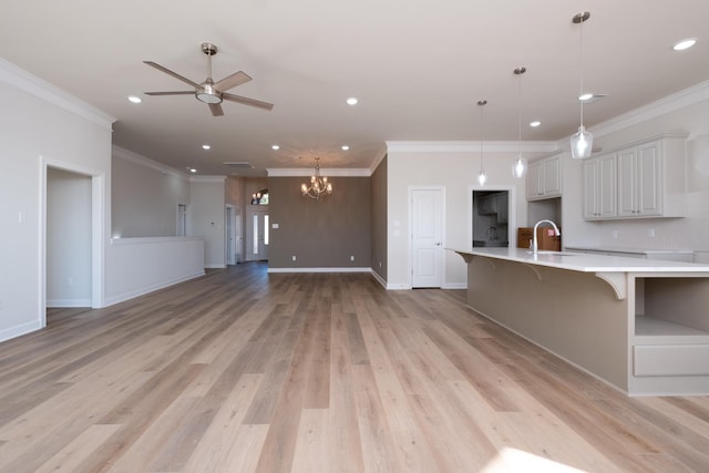 kitchen featuring a kitchen bar, sink, white cabinetry, pendant lighting, and light hardwood / wood-style floors