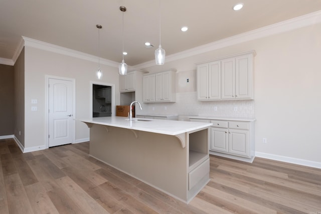 kitchen with white cabinetry, pendant lighting, sink, and a large island with sink