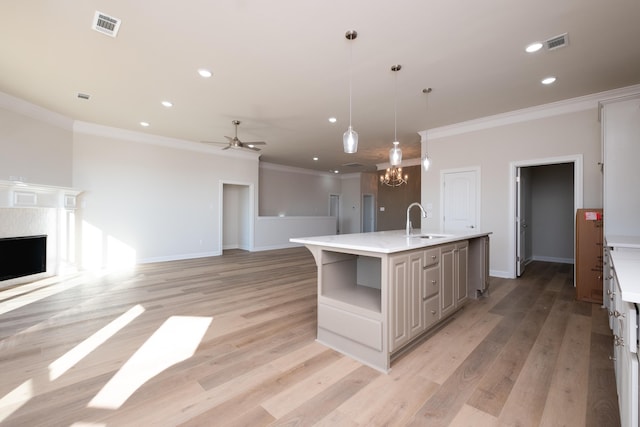 kitchen with pendant lighting, sink, light hardwood / wood-style floors, and a center island with sink