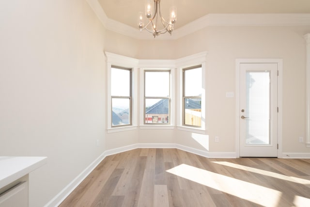 entrance foyer with an inviting chandelier, ornamental molding, a wealth of natural light, and light hardwood / wood-style floors