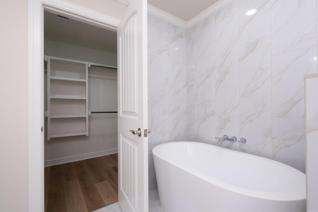 bathroom featuring a washtub, crown molding, tile walls, and hardwood / wood-style flooring