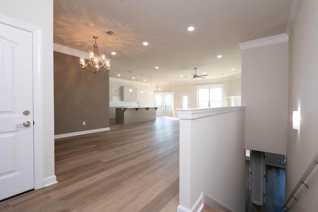 interior space with hardwood / wood-style flooring, ornamental molding, sink, and ceiling fan with notable chandelier