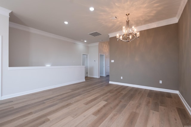 empty room with ornamental molding, a chandelier, and light hardwood / wood-style flooring