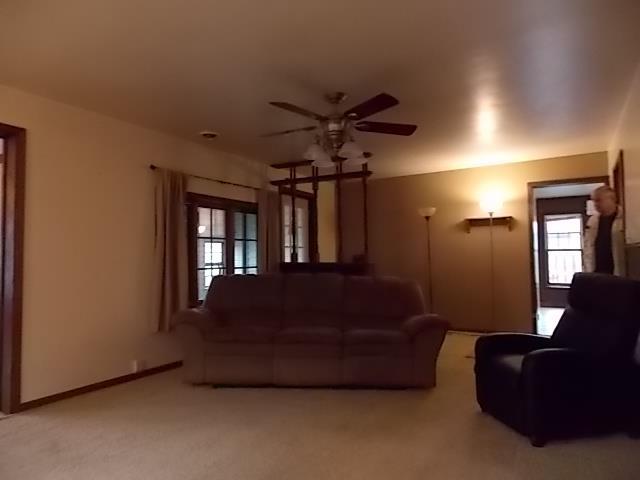 unfurnished living room featuring light carpet and ceiling fan