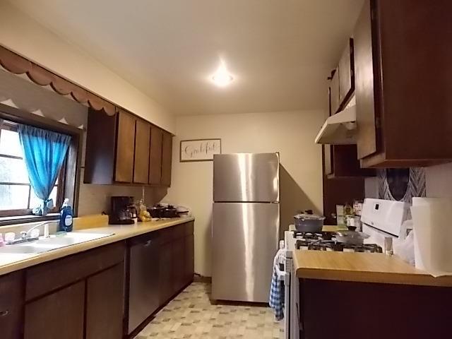 kitchen featuring stainless steel refrigerator, dark brown cabinetry, sink, and white range with gas stovetop