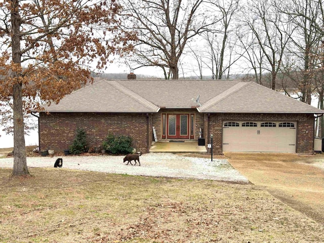 ranch-style home with a garage, a front yard, and french doors