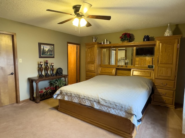 bedroom with ceiling fan, light carpet, and a textured ceiling