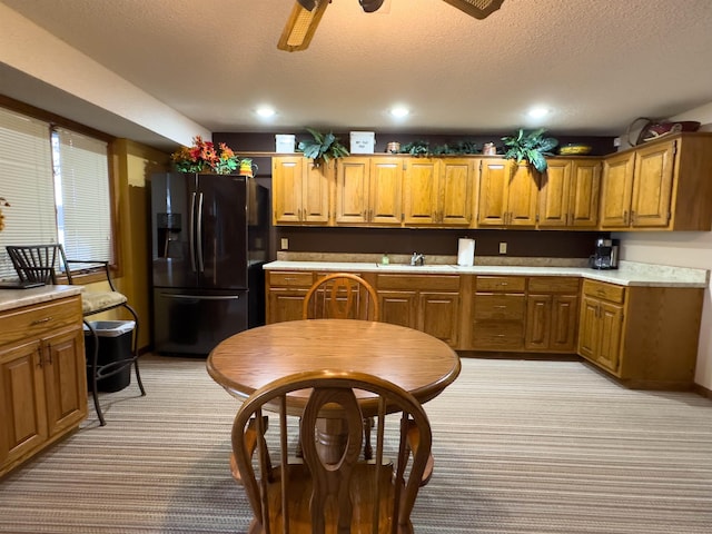 kitchen featuring black fridge with ice dispenser, sink, light colored carpet, a textured ceiling, and ceiling fan