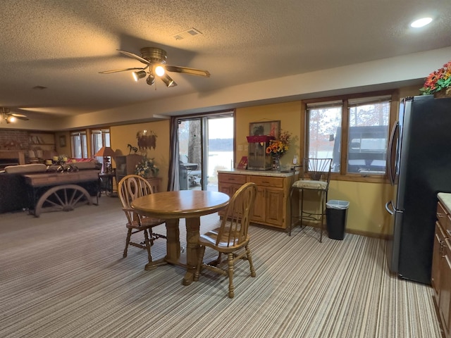 carpeted dining area featuring ceiling fan and a textured ceiling