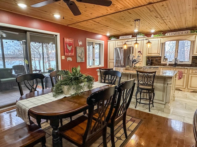 dining space featuring ceiling fan, light wood-type flooring, sink, and wood ceiling