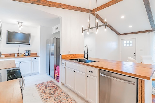 kitchen with butcher block counters, sink, decorative light fixtures, appliances with stainless steel finishes, and white cabinets